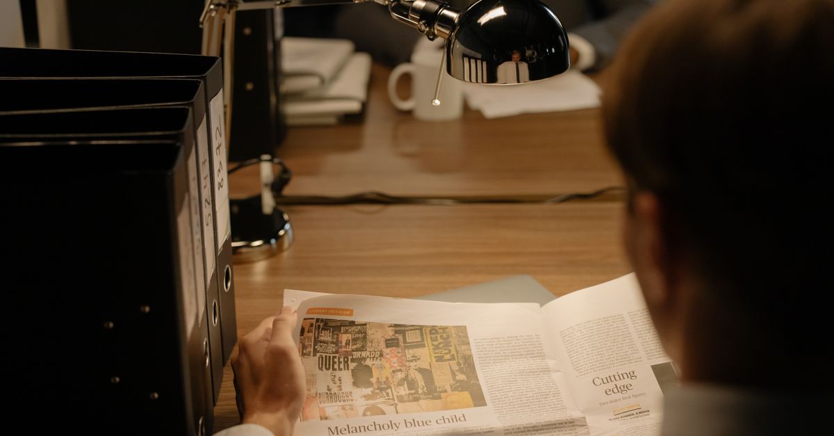 Une personne lit un document à son bureau, sous une lampe