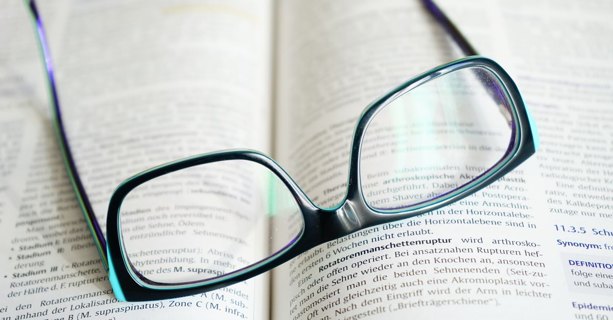 Des lunettes posées sur un ouvrage ouvert, page pleine de texte