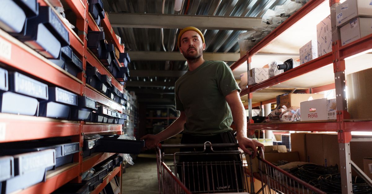 Un préparateur de commande vérifie les pièces d'un appareil sur une étagère d'entrepôt