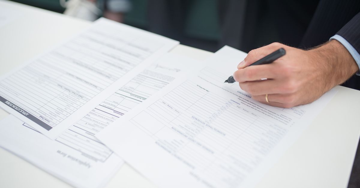Une main signe un document administratif sur un bureau